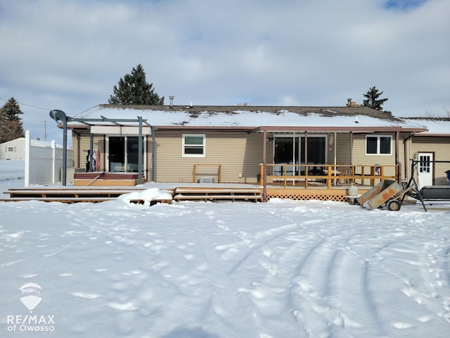 snow covered rear of property with a deck