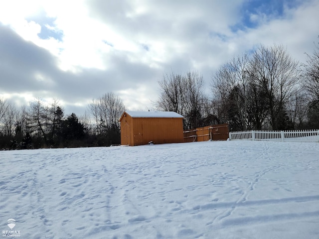 snowy yard featuring a storage shed