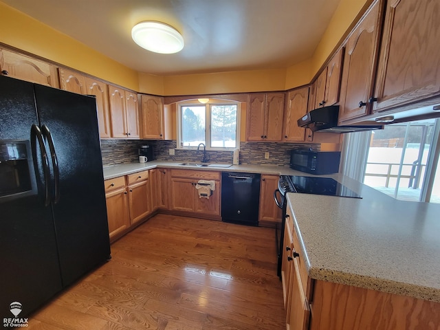 kitchen with light wood-type flooring, sink, backsplash, and black appliances