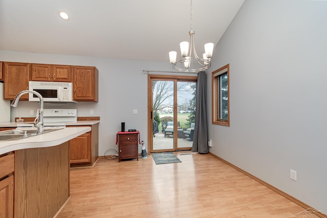 kitchen with pendant lighting, lofted ceiling, sink, a notable chandelier, and light wood-type flooring