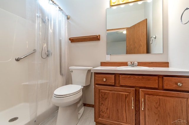 bathroom featuring toilet, vanity, and a shower