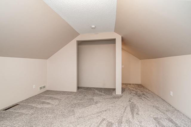 bonus room featuring lofted ceiling, carpet floors, and a textured ceiling