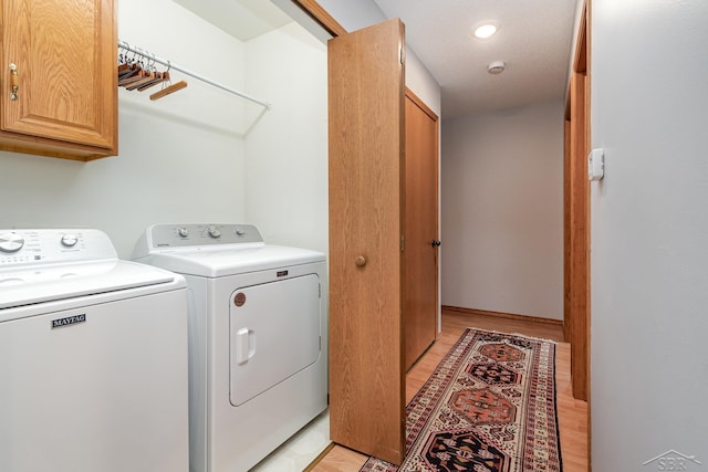 clothes washing area with cabinets and independent washer and dryer