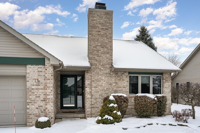 snow covered property entrance featuring a garage