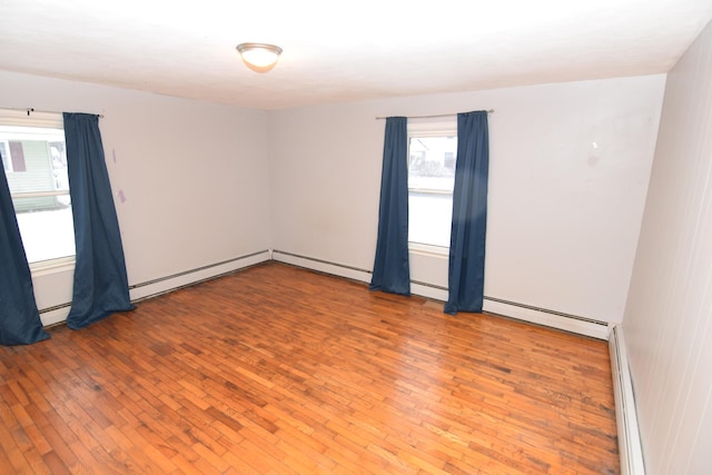 unfurnished room featuring baseboard heating and hardwood / wood-style floors