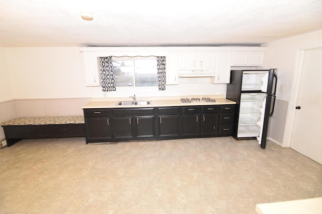 kitchen with sink, white cabinets, black fridge, and white gas stovetop