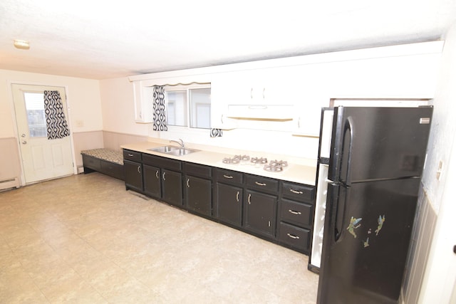 kitchen featuring black refrigerator, white cabinetry, and sink