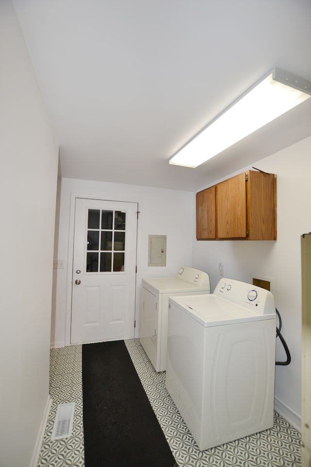 laundry area featuring washing machine and dryer, electric panel, and cabinets