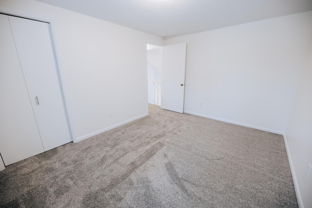 unfurnished bedroom featuring a closet and light carpet