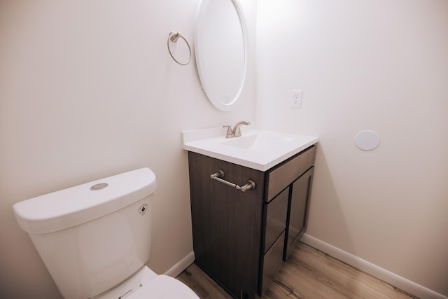 bathroom with toilet, vanity, and hardwood / wood-style flooring