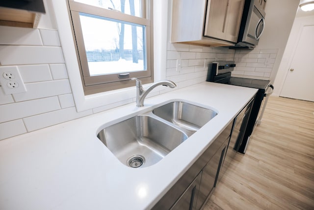 kitchen featuring decorative backsplash, sink, light hardwood / wood-style flooring, and stainless steel appliances