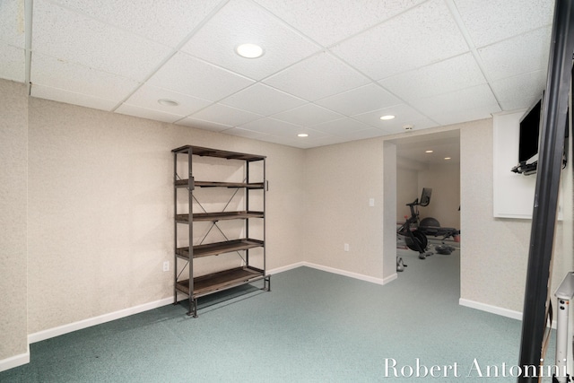 basement featuring a paneled ceiling and carpet