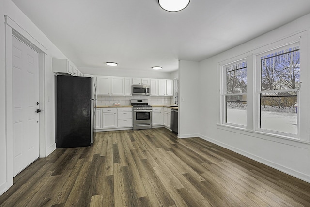 kitchen featuring appliances with stainless steel finishes, decorative backsplash, dark hardwood / wood-style floors, white cabinets, and sink