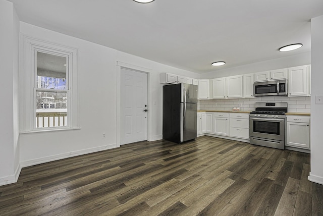 kitchen with decorative backsplash, white cabinets, appliances with stainless steel finishes, and dark wood-type flooring