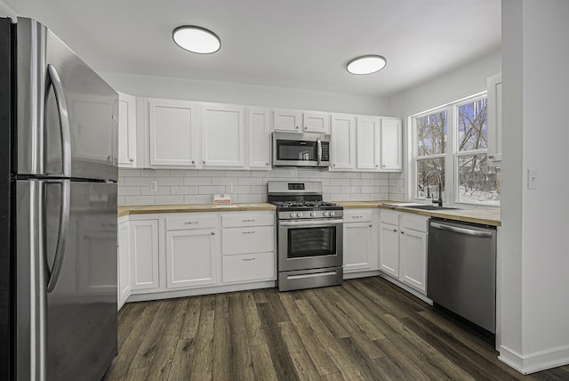 kitchen featuring appliances with stainless steel finishes, wood counters, white cabinetry, sink, and dark hardwood / wood-style floors