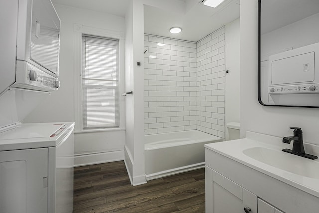 bathroom with stacked washing maching and dryer, wood-type flooring, tiled shower / bath combo, and vanity