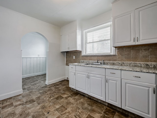 kitchen featuring decorative backsplash, white cabinets, and sink