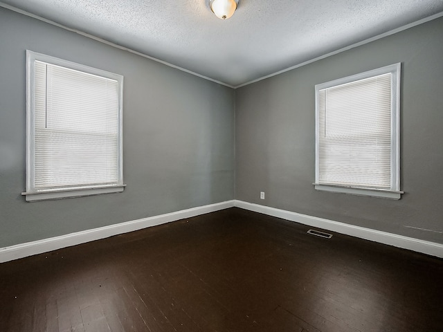 empty room with a textured ceiling, dark hardwood / wood-style flooring, and ornamental molding