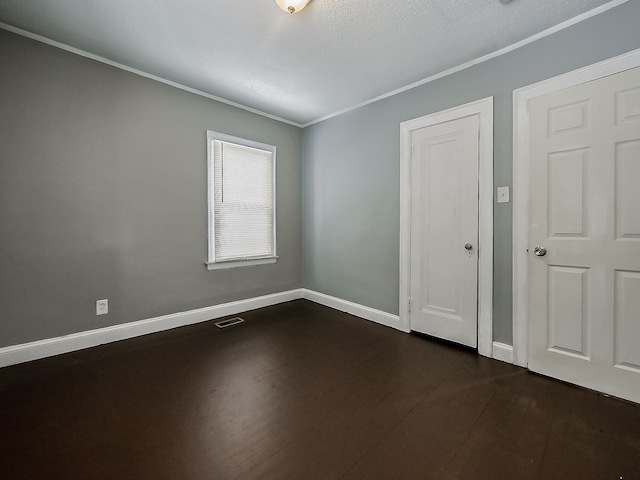 spare room featuring dark wood-type flooring and crown molding