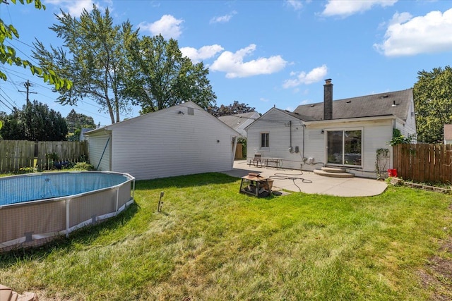 rear view of property featuring a fenced in pool, a patio area, and a yard