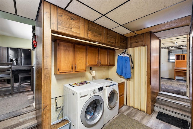 laundry room with independent washer and dryer, light hardwood / wood-style floors, and cabinets