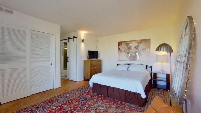 bedroom featuring a closet, parquet floors, and a barn door