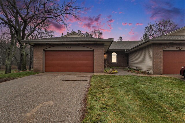 single story home featuring a garage and a lawn