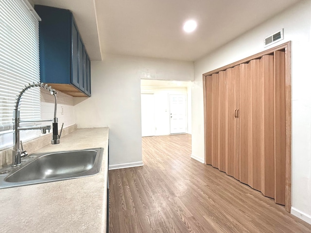 kitchen with hardwood / wood-style flooring, sink, and blue cabinets