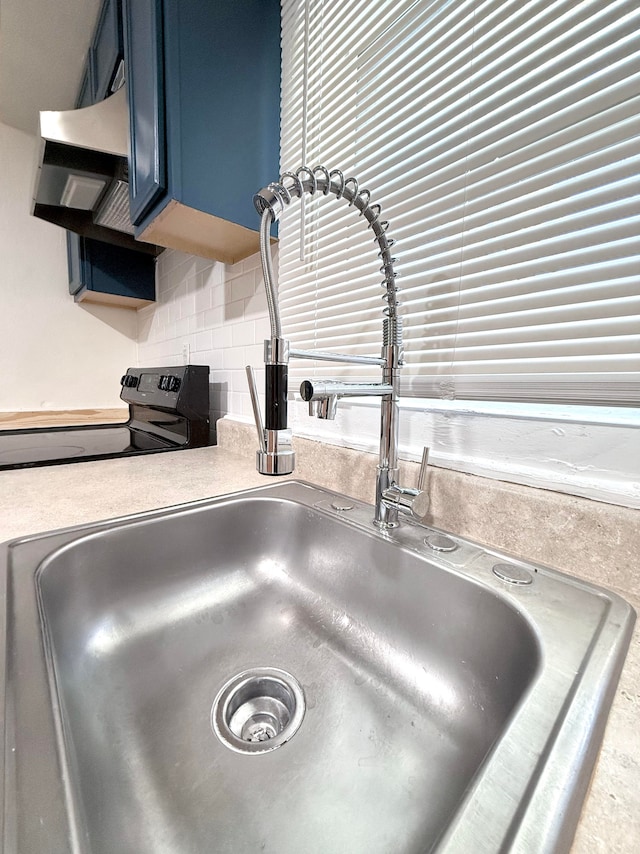 room details with tasteful backsplash, electric range, sink, and blue cabinetry