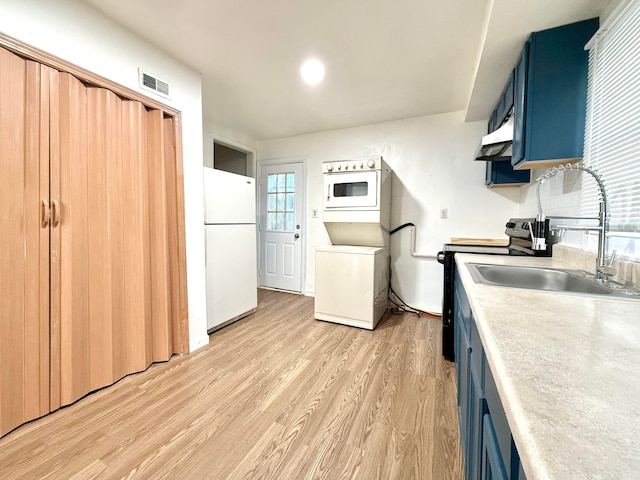 kitchen with stacked washer / drying machine, white fridge, light hardwood / wood-style floors, black electric range oven, and blue cabinets