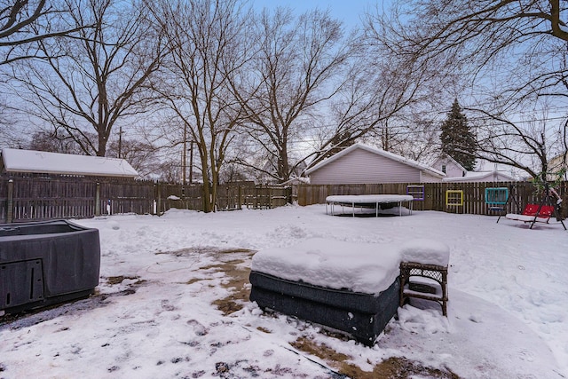 yard layered in snow with a trampoline