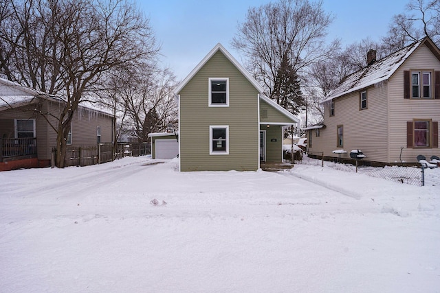 snow covered rear of property with a garage and an outdoor structure