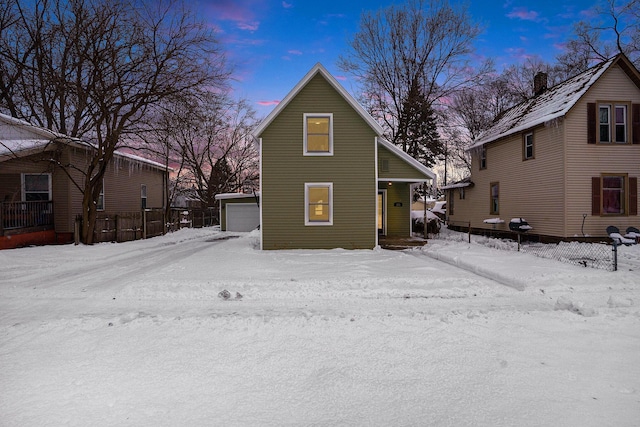 snow covered property with an outdoor structure and a garage