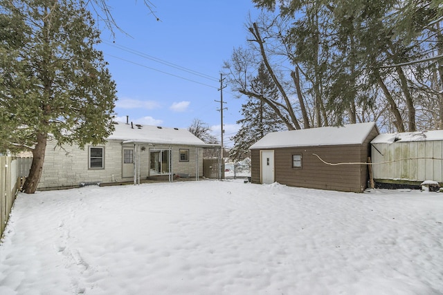 snow covered back of property featuring an outbuilding