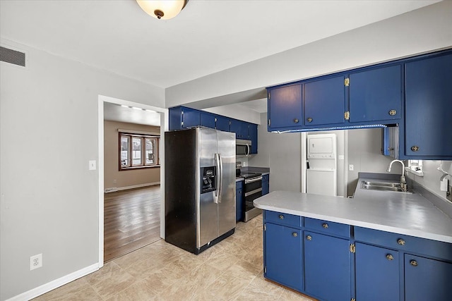 kitchen featuring sink, appliances with stainless steel finishes, blue cabinetry, and stacked washing maching and dryer