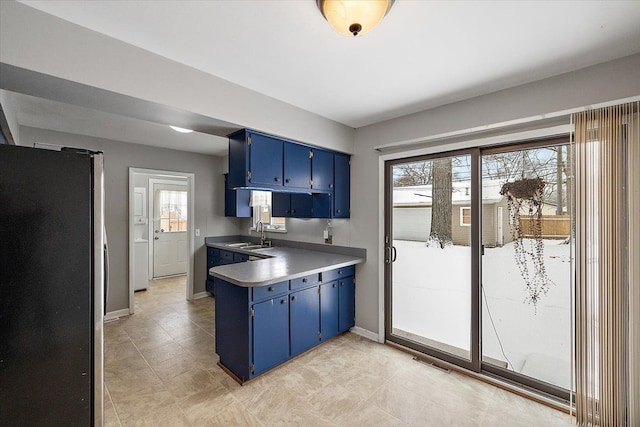 kitchen with sink, stainless steel fridge, a wealth of natural light, and blue cabinetry