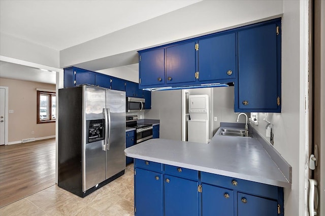 kitchen with sink, appliances with stainless steel finishes, light hardwood / wood-style flooring, and blue cabinets