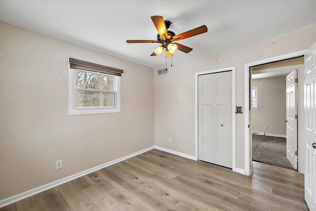 unfurnished bedroom featuring ceiling fan, a closet, and light wood-type flooring