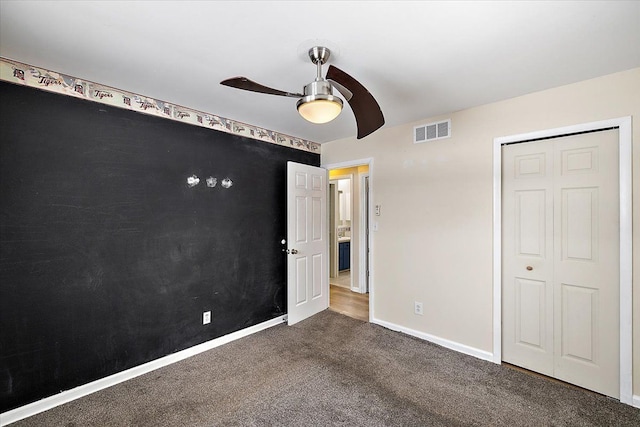 unfurnished bedroom featuring ceiling fan, a closet, and dark carpet