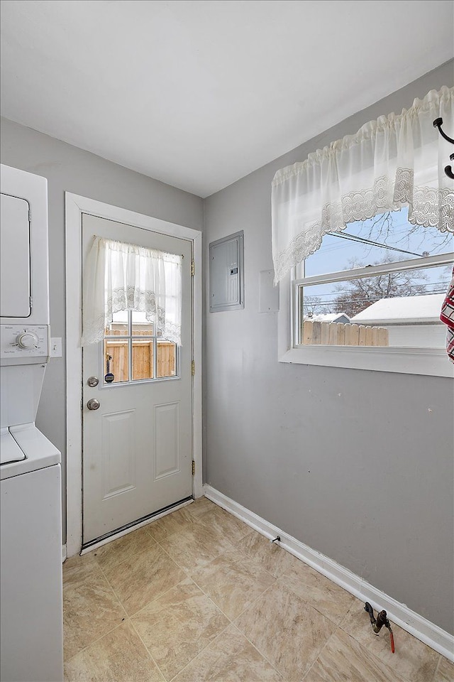 doorway with a wealth of natural light, stacked washer and clothes dryer, and electric panel