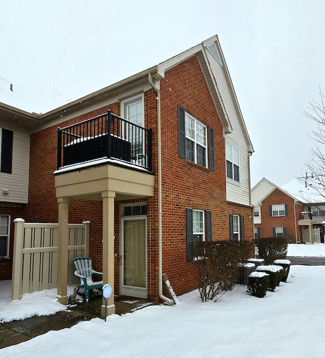 snow covered rear of property featuring a balcony