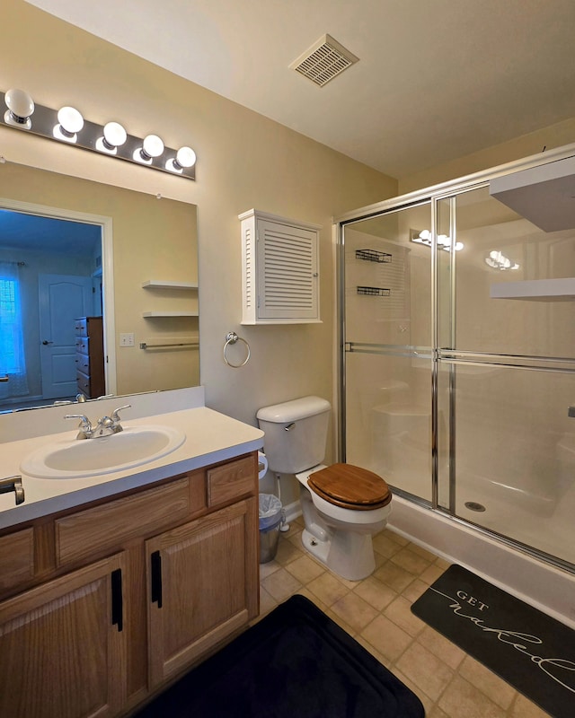 bathroom featuring toilet, vanity, an enclosed shower, and tile patterned floors