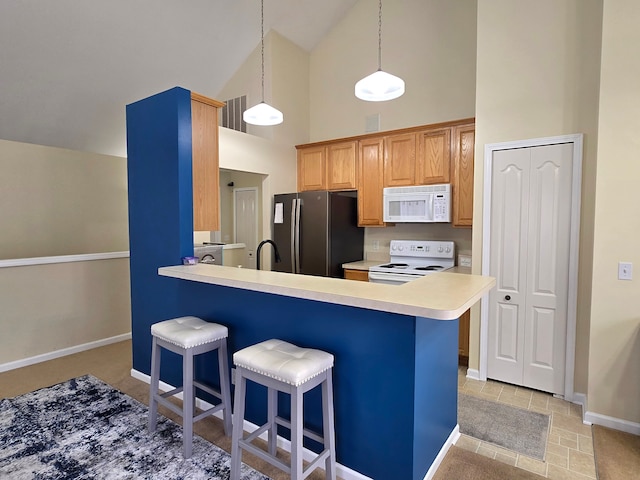 kitchen with a kitchen bar, kitchen peninsula, white appliances, high vaulted ceiling, and pendant lighting