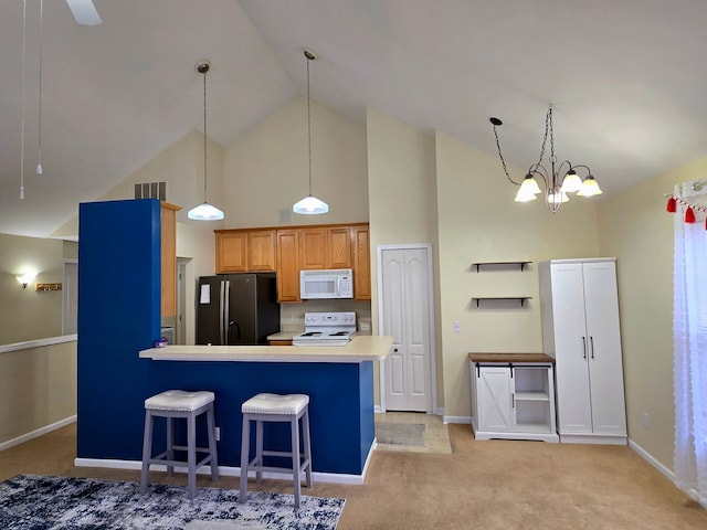 kitchen with high vaulted ceiling, white appliances, a kitchen bar, and pendant lighting