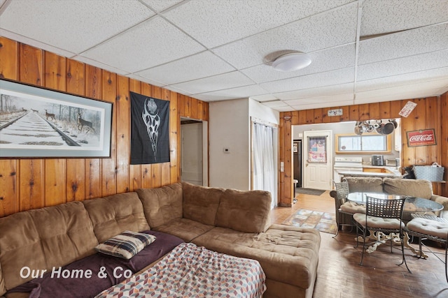 living room featuring a drop ceiling and wood walls