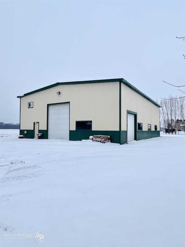 snow covered structure with a garage