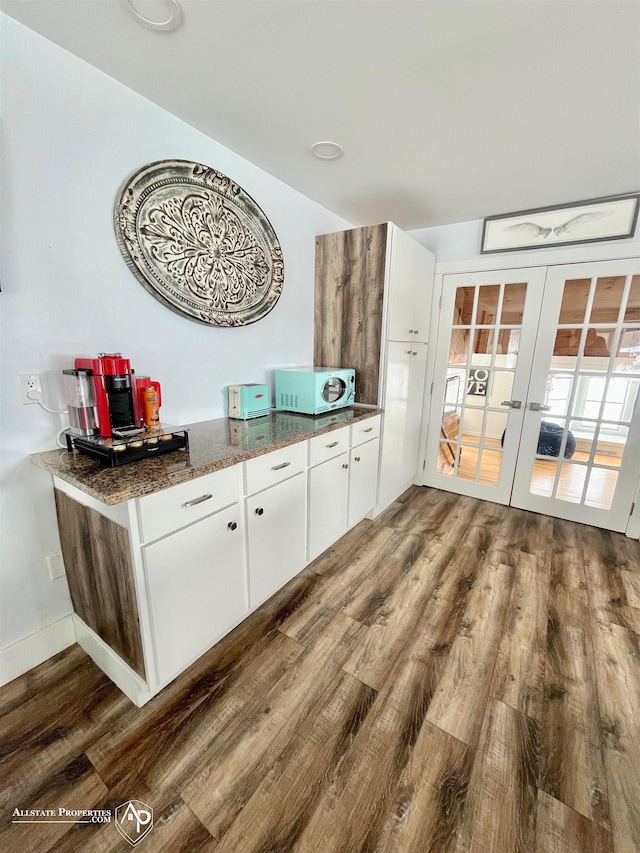 kitchen with wood-type flooring, white cabinetry, french doors, and dark stone countertops