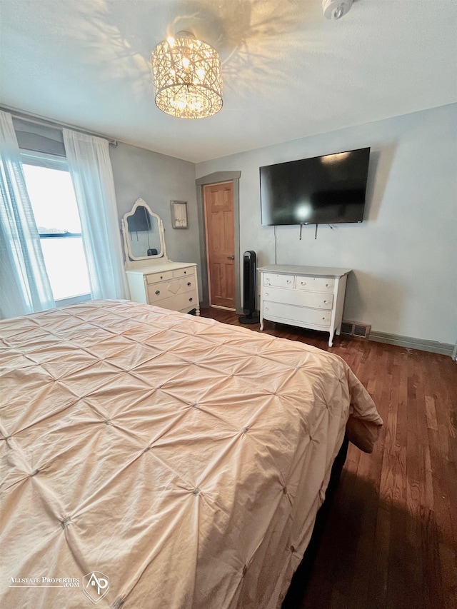 bedroom with hardwood / wood-style floors and an inviting chandelier