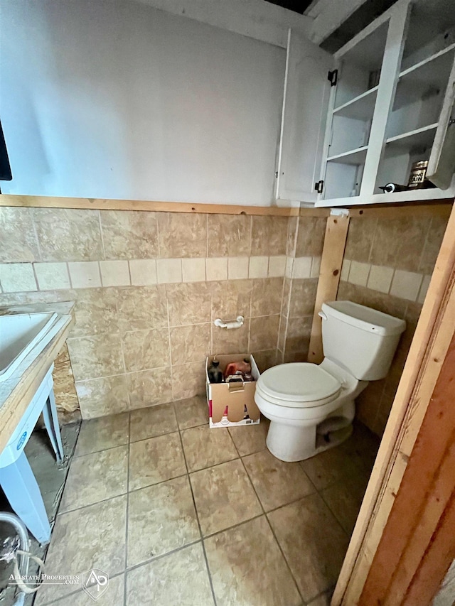 bathroom with tile walls, toilet, and tile patterned flooring