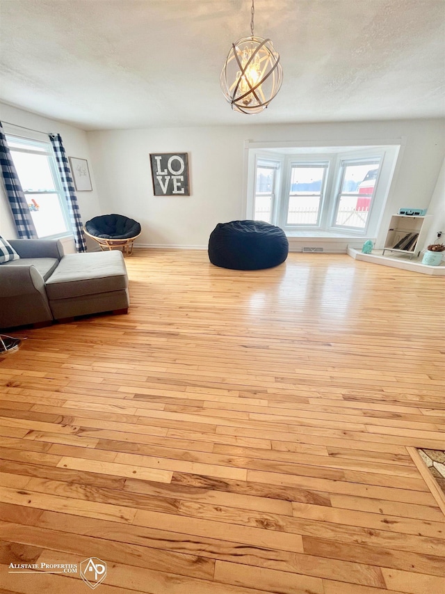 interior space with a textured ceiling, light hardwood / wood-style flooring, an inviting chandelier, and a healthy amount of sunlight